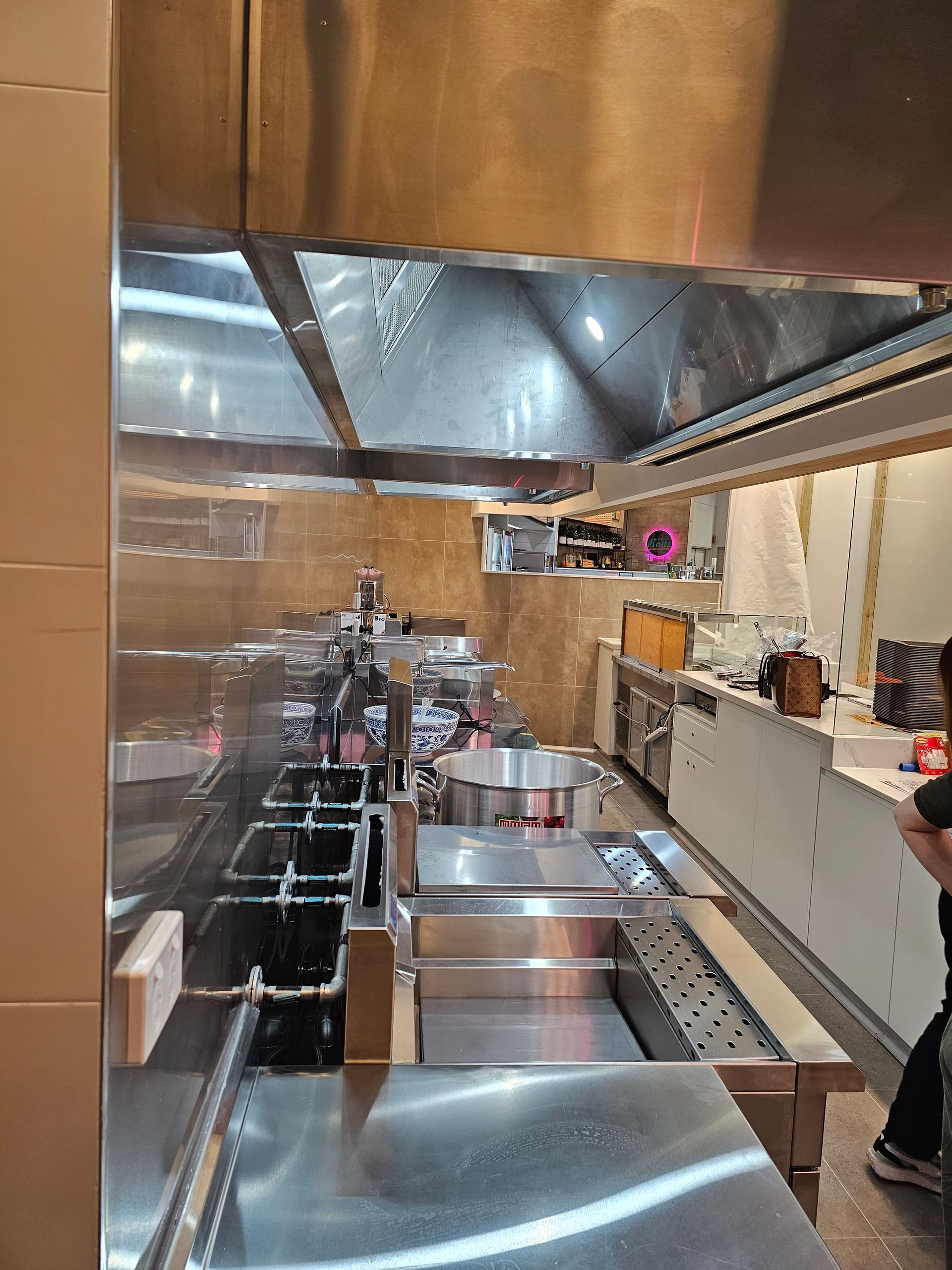 A man is standing in a kitchen with a lot of stainless steel appliances.