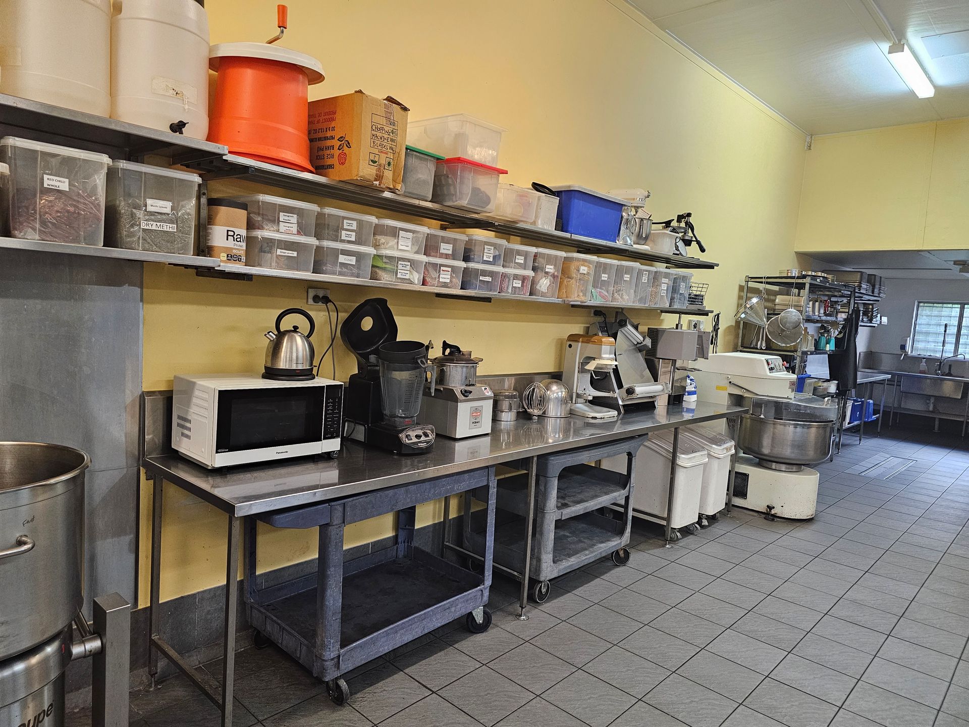 A kitchen with a lot of appliances on the counters and shelves.
