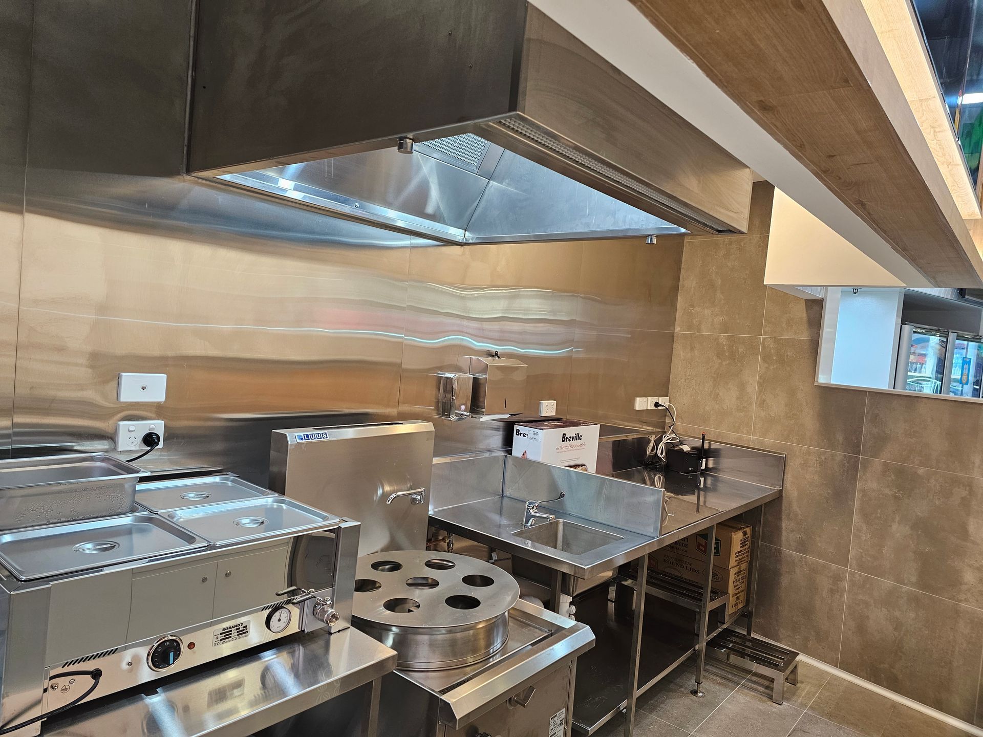A kitchen with stainless steel appliances and a hood.