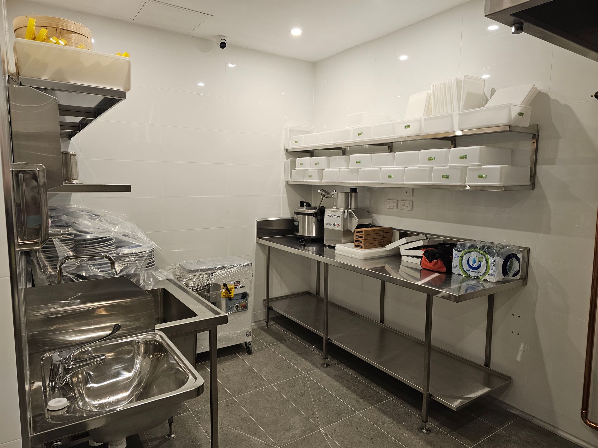 A man is working on a stainless steel counter in a kitchen.