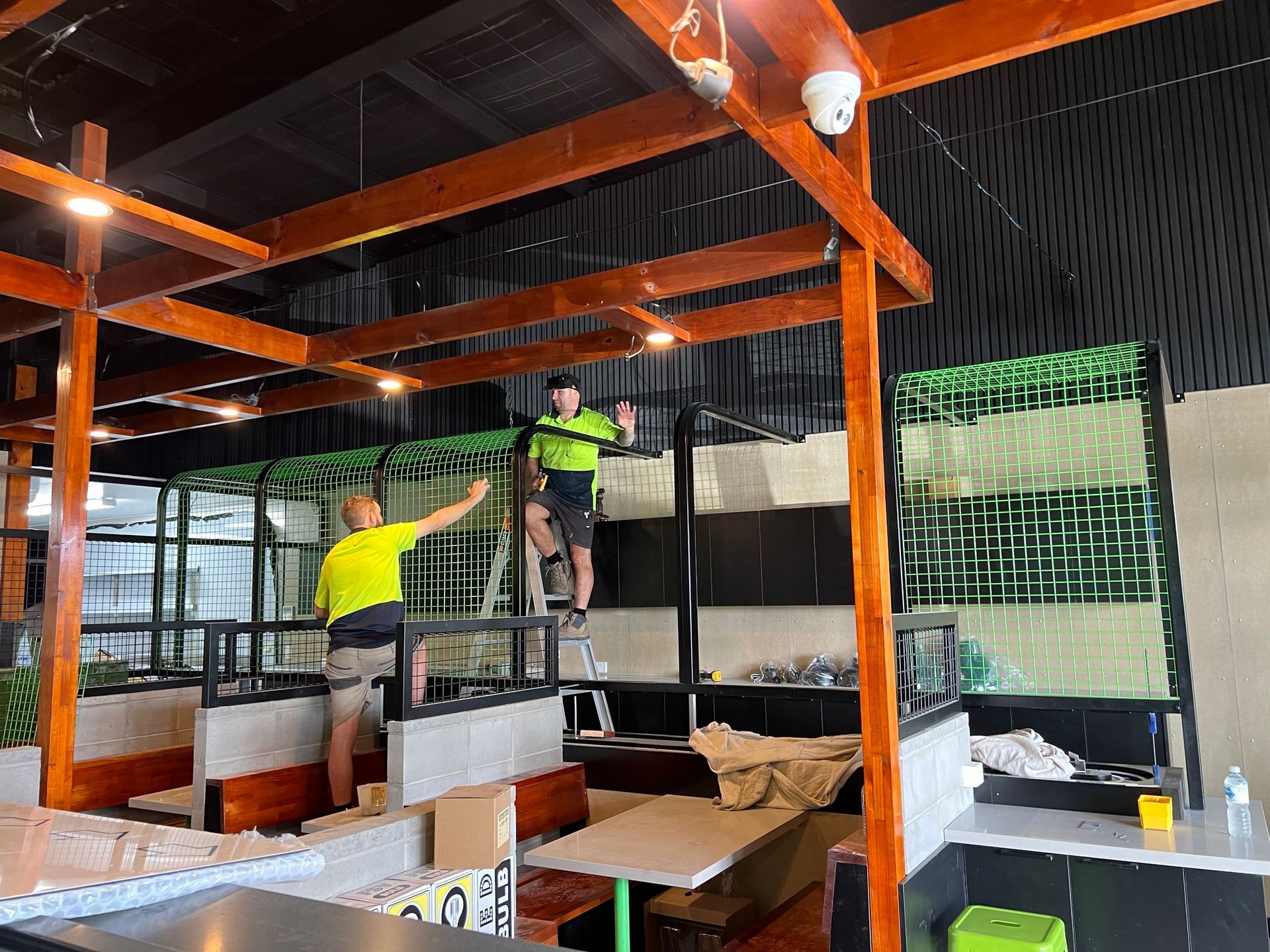 Two men are working on the ceiling of a restaurant.