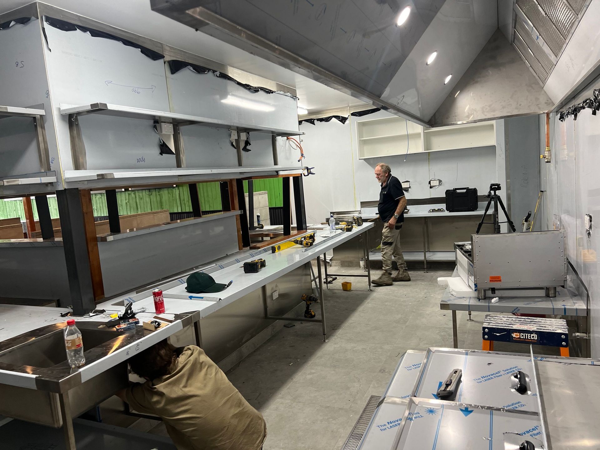 A man is working in a kitchen with stainless steel counter tops.