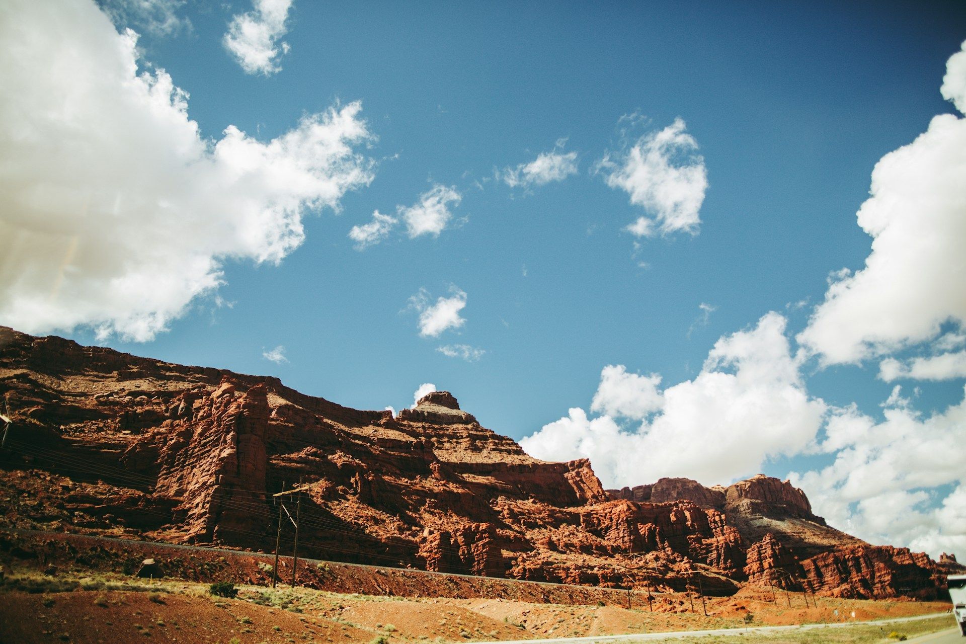 Red rock formations under a partly cloudy blue sky, with a structure on top.