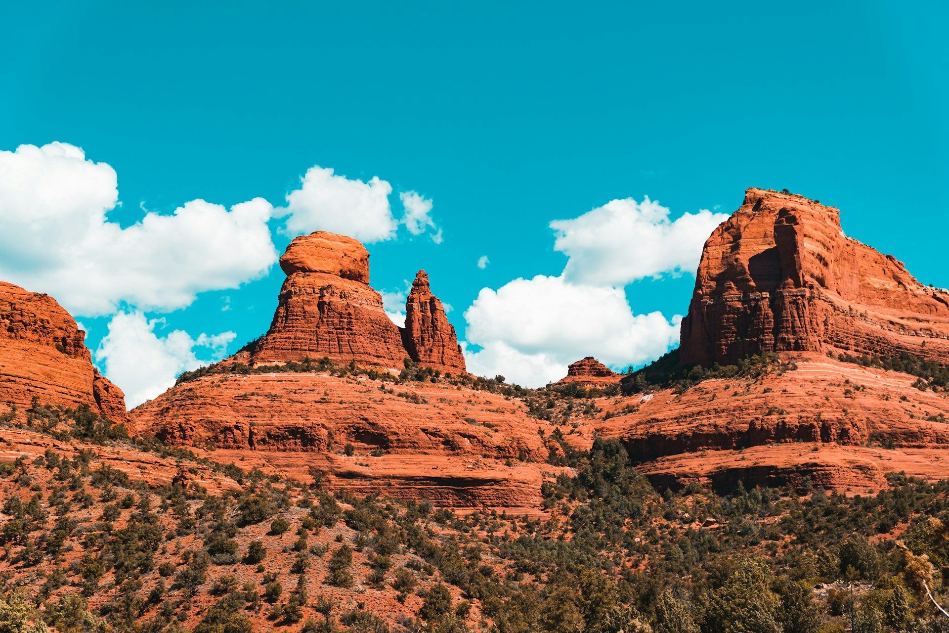 Red rock formations under a bright blue sky with white clouds; Southwestern landscape.