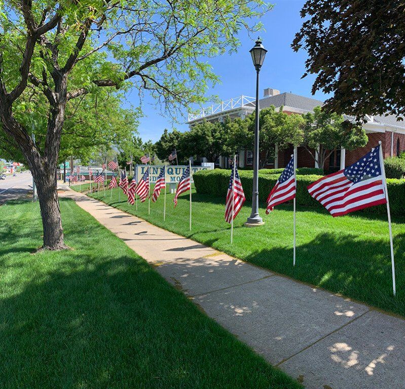 A row of american flags are lined up along a sidewalk