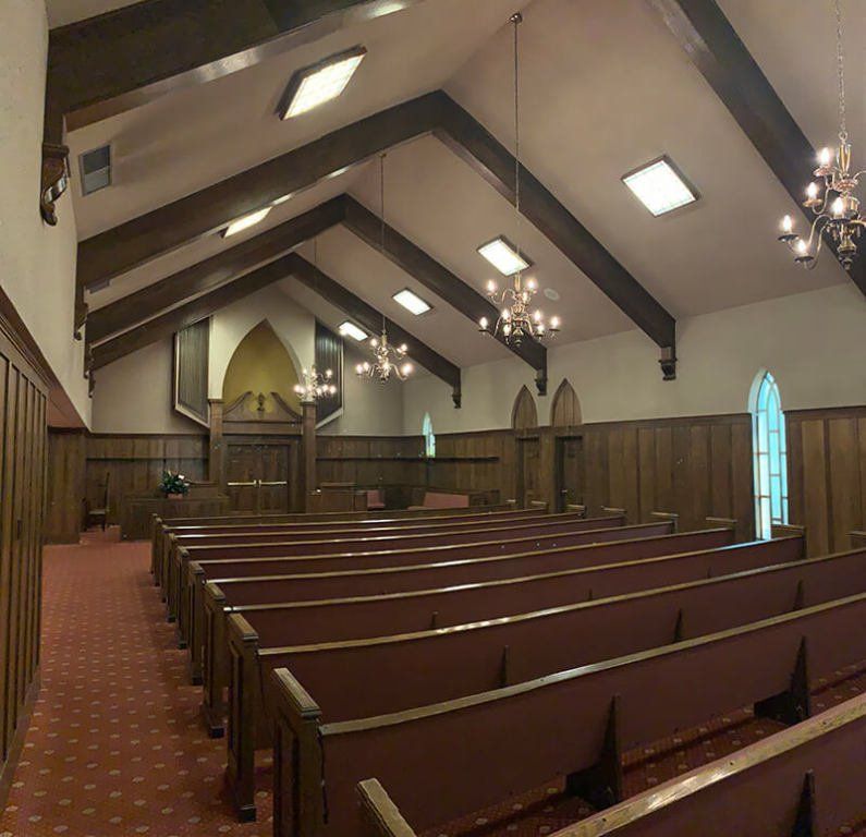 Rows of wooden benches in a church with a vaulted ceiling