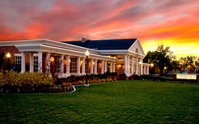 A large white house with a sunset in the background