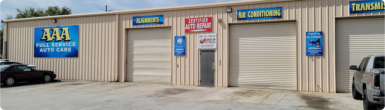 Auto repair shop exterior with garage doors and signs for services. | AAA Full Service Auto Care
