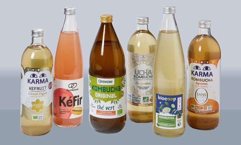 Six glass bottles of kombucha and kefir in varying colors, labels visible.