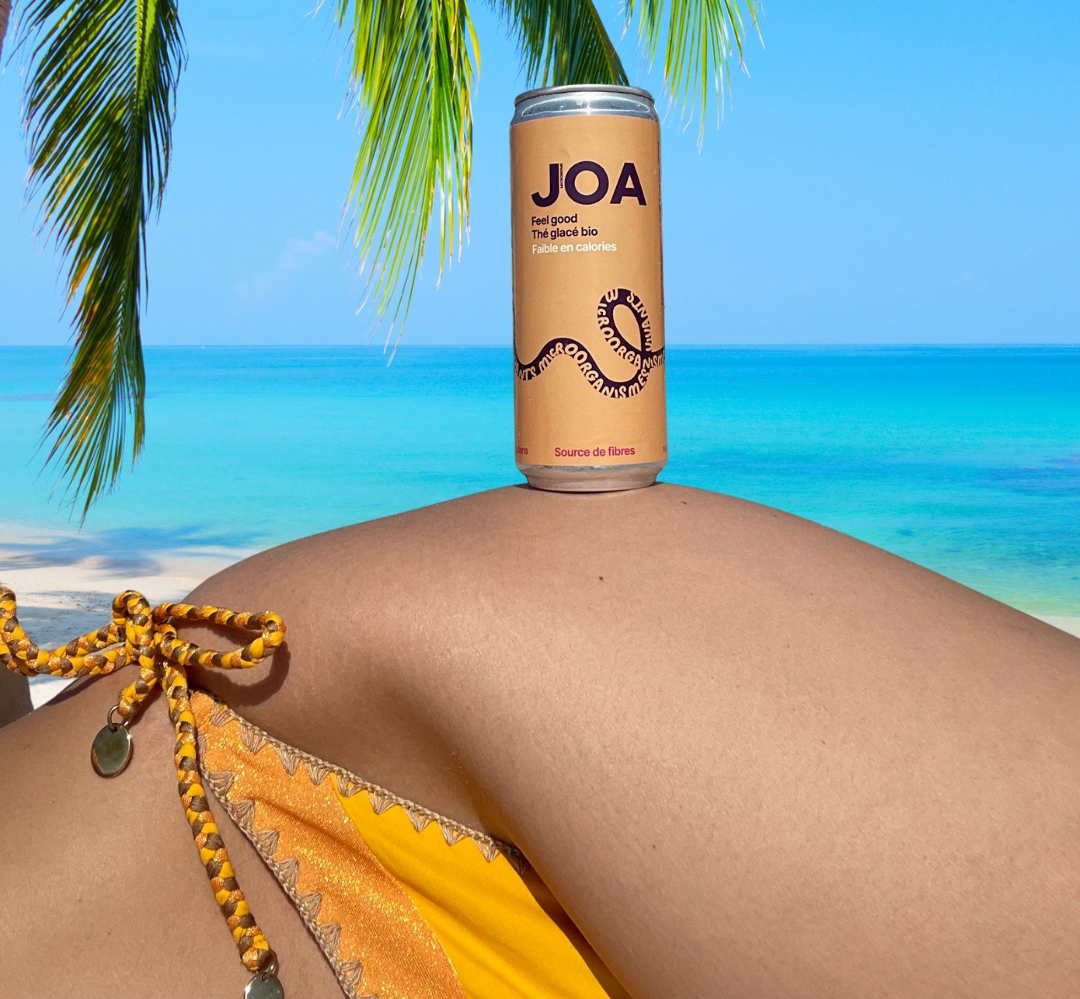 Une femme est allongée sur la plage avec une canette de joa sur le ventre.