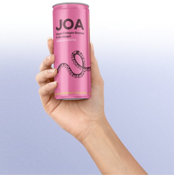 Une main tient une canette rose de Joa