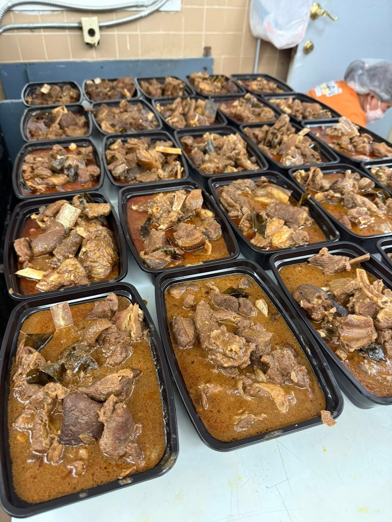 Rows of prepared meals in black containers, ready for service.