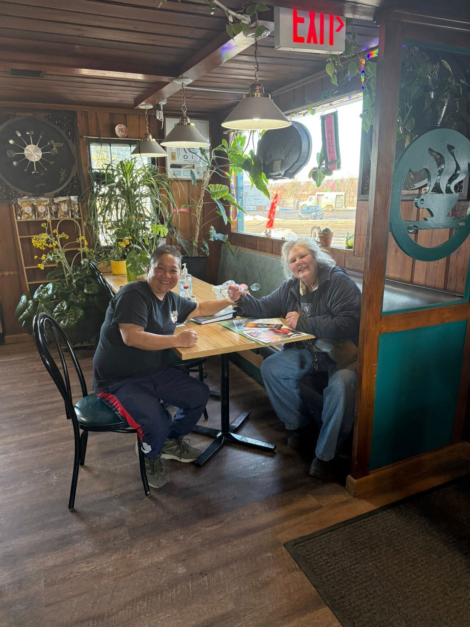 Two people seated at a table in a restaurant. They are looking at the food on their plates with smiles.