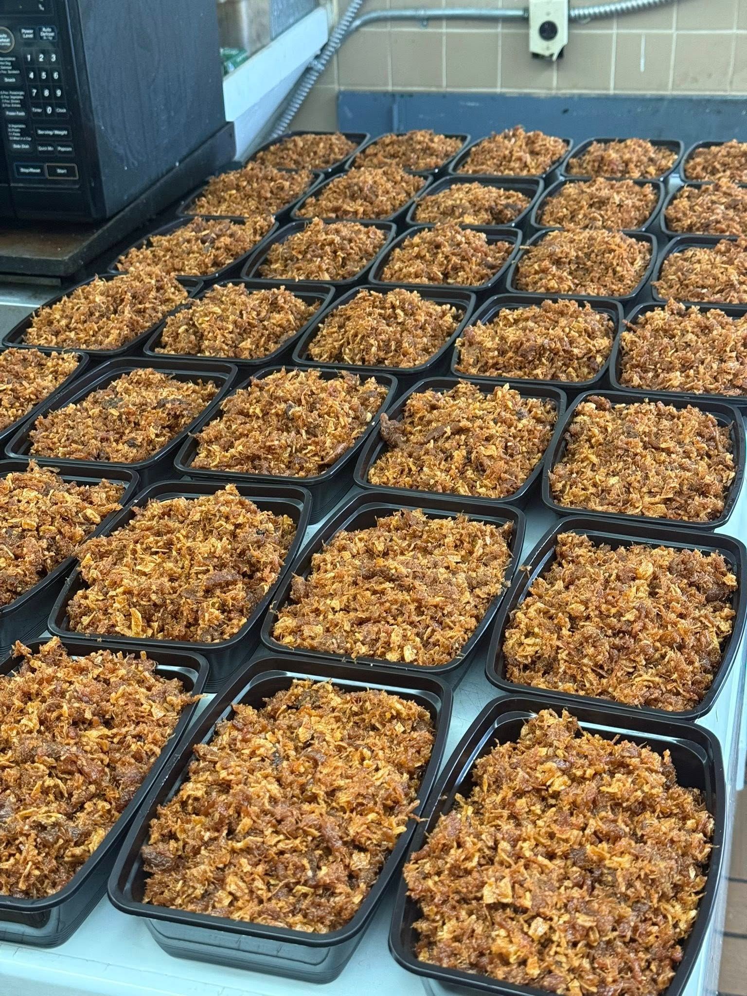 Prepared meals in black containers, ready for distribution.