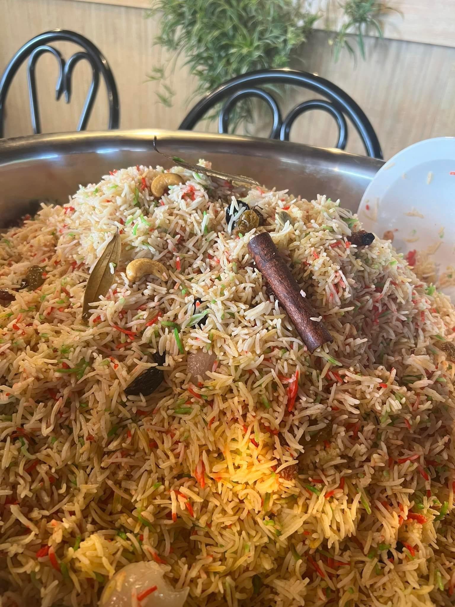 Large bowl of colorful biryani, with cinnamon stick and bay leaves.