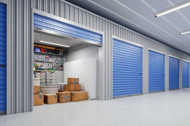 A row of storage units with blue doors and boxes in them.