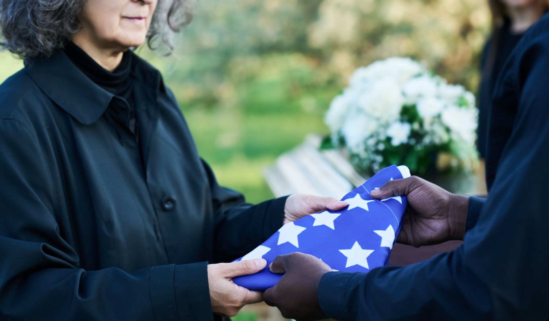 A man in a military uniform is holding an American flag in his hands.