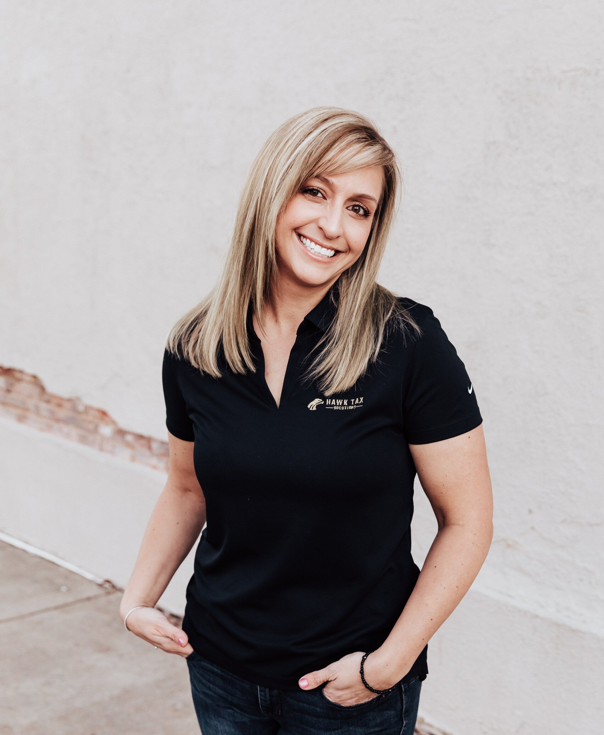 a woman in a black shirt is smiling in front of a white wall .