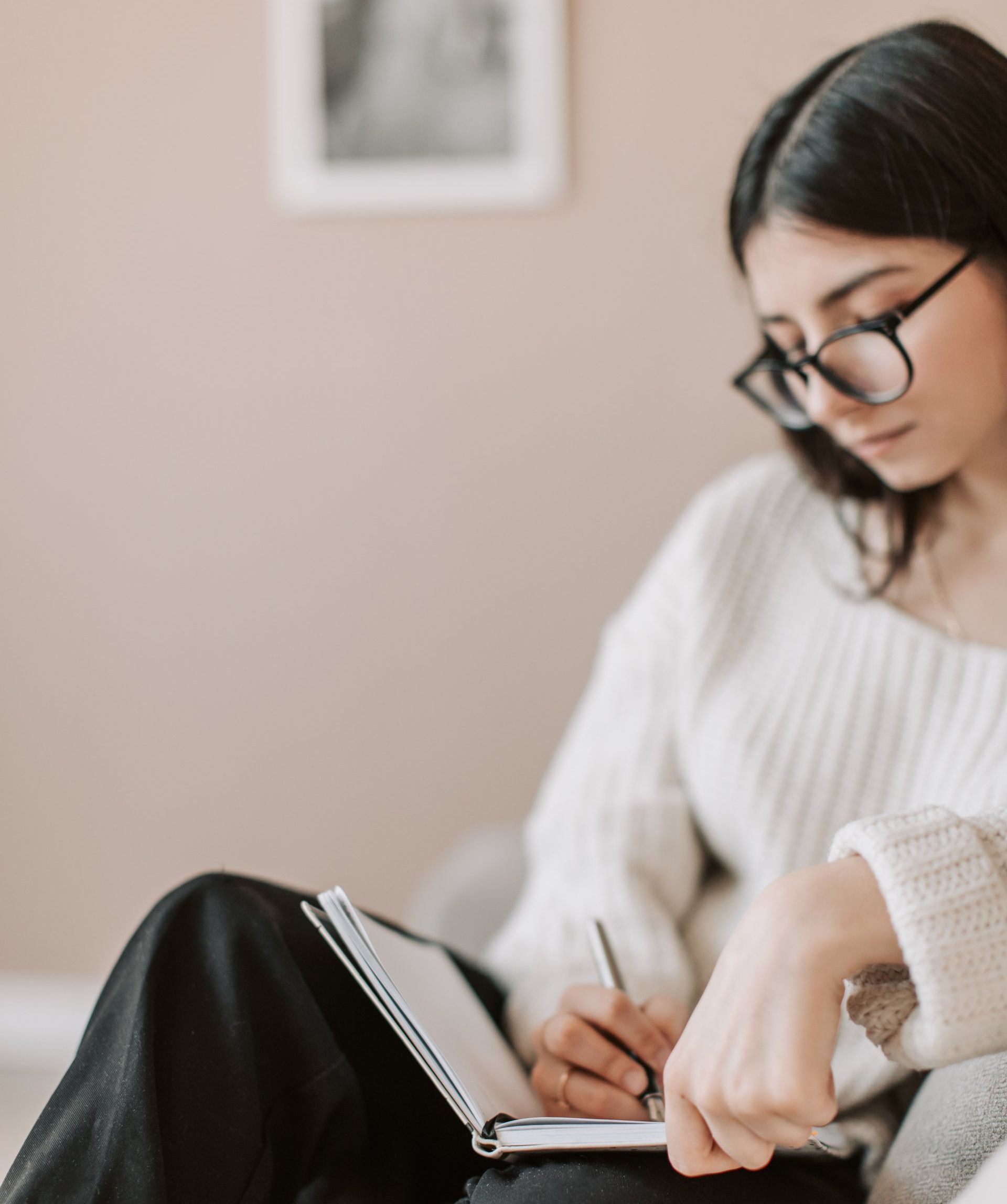 Woman in white sweater planning her tax return in a notebook
