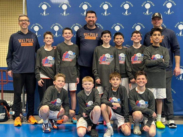 Group of 11 people posing in front of a blue backdrop, wearing matching dark team shirts.