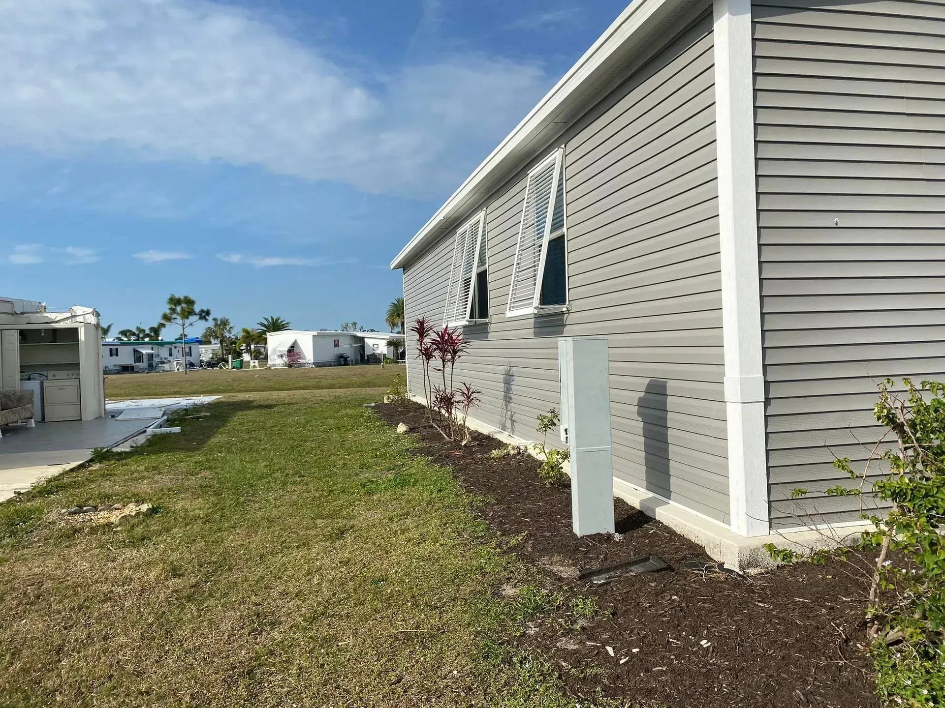 Gray house with white trim, green grass, and blue sky. Gray house with white trim, green grass, and blue sky.