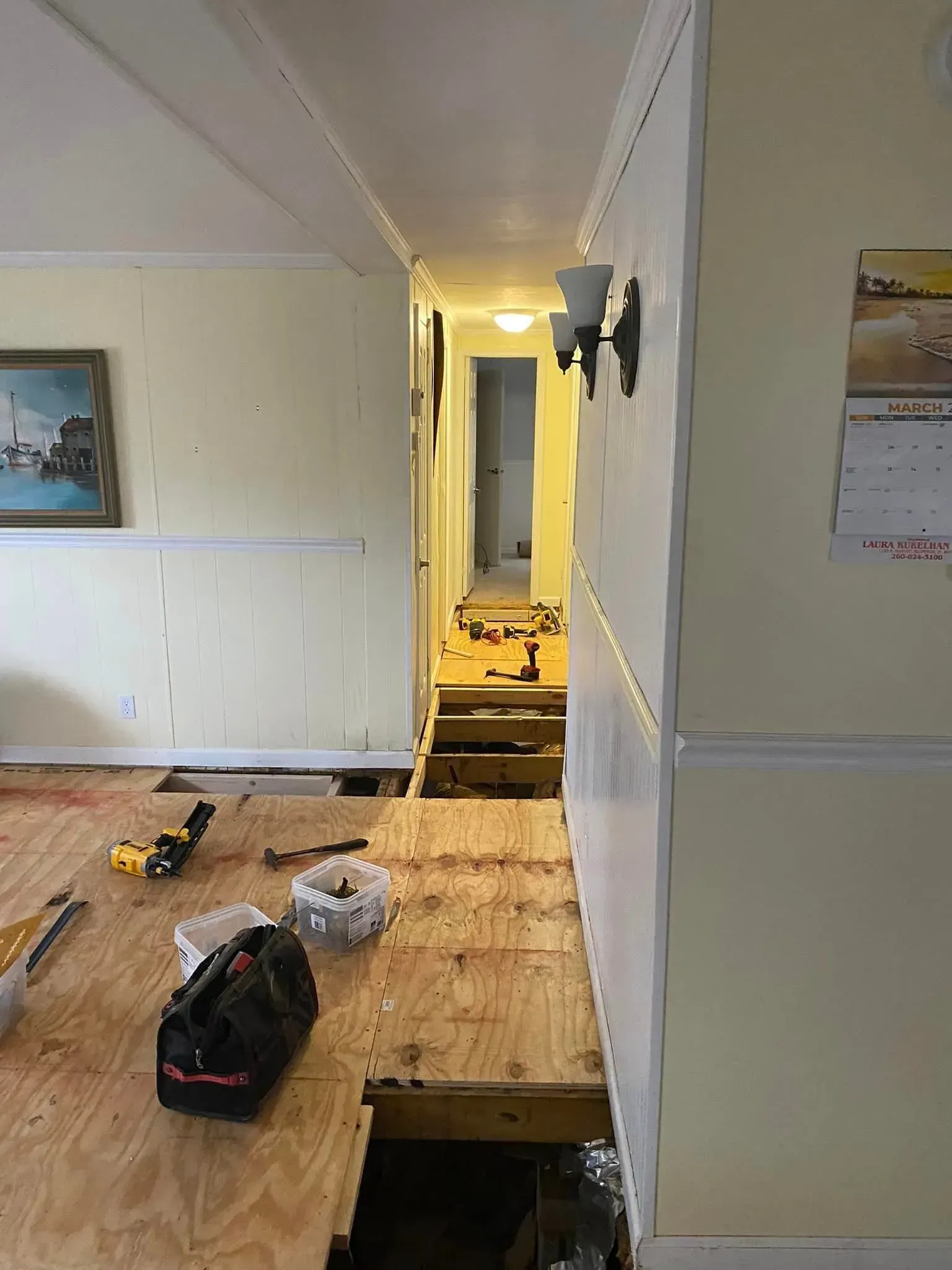 Interior room with exposed floorboards and hallway under renovation. Tools and materials are scattered. Interior room with exposed floorboards and hallway under renovation. Tools and materials are scattered.