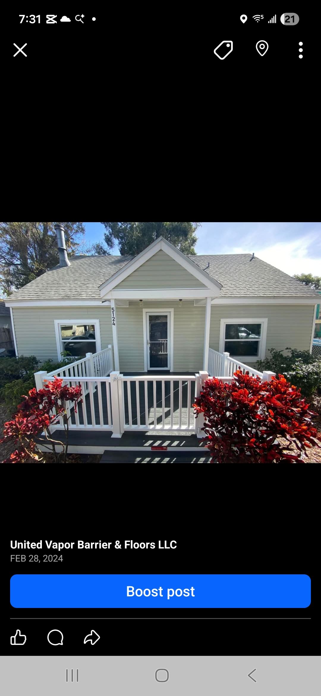 Small, light green house with white trim, red bushes, and a white picket fence on the porch.