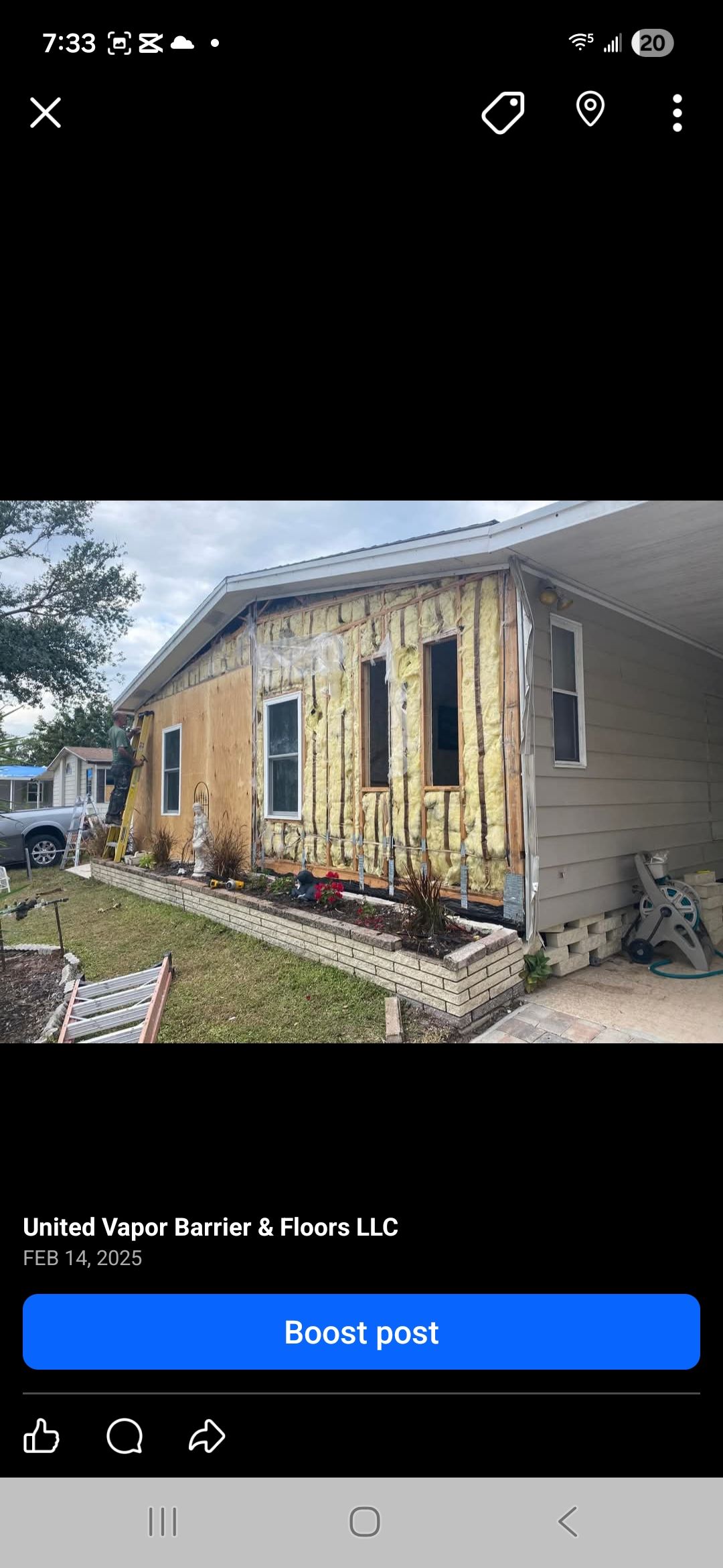 House with siding partially removed, showing wooden framing. Landscaping in front.