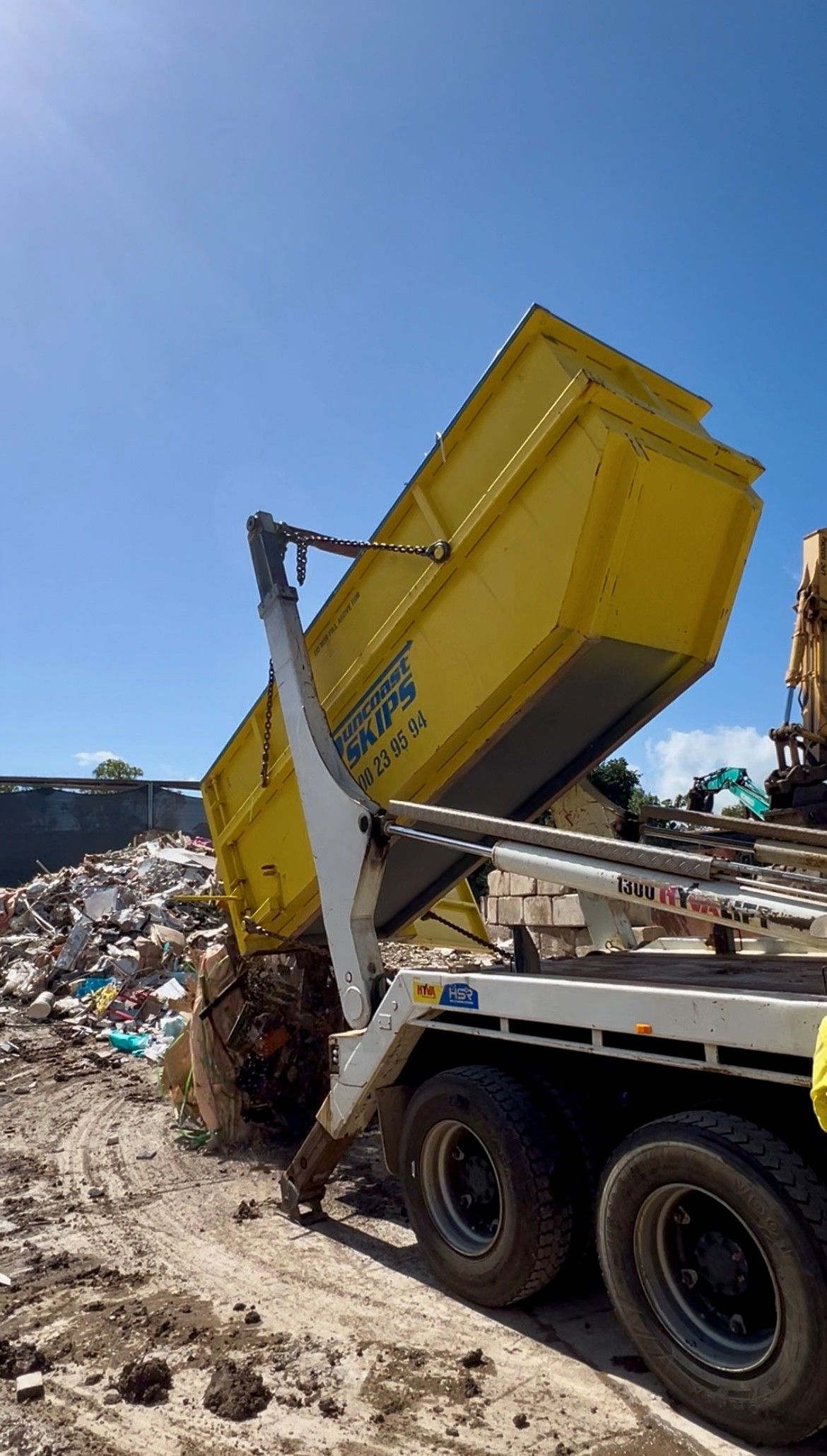 A Yellow hook bin being lifted by a crane — Suncoast Skips in Coolum Beach, QLD