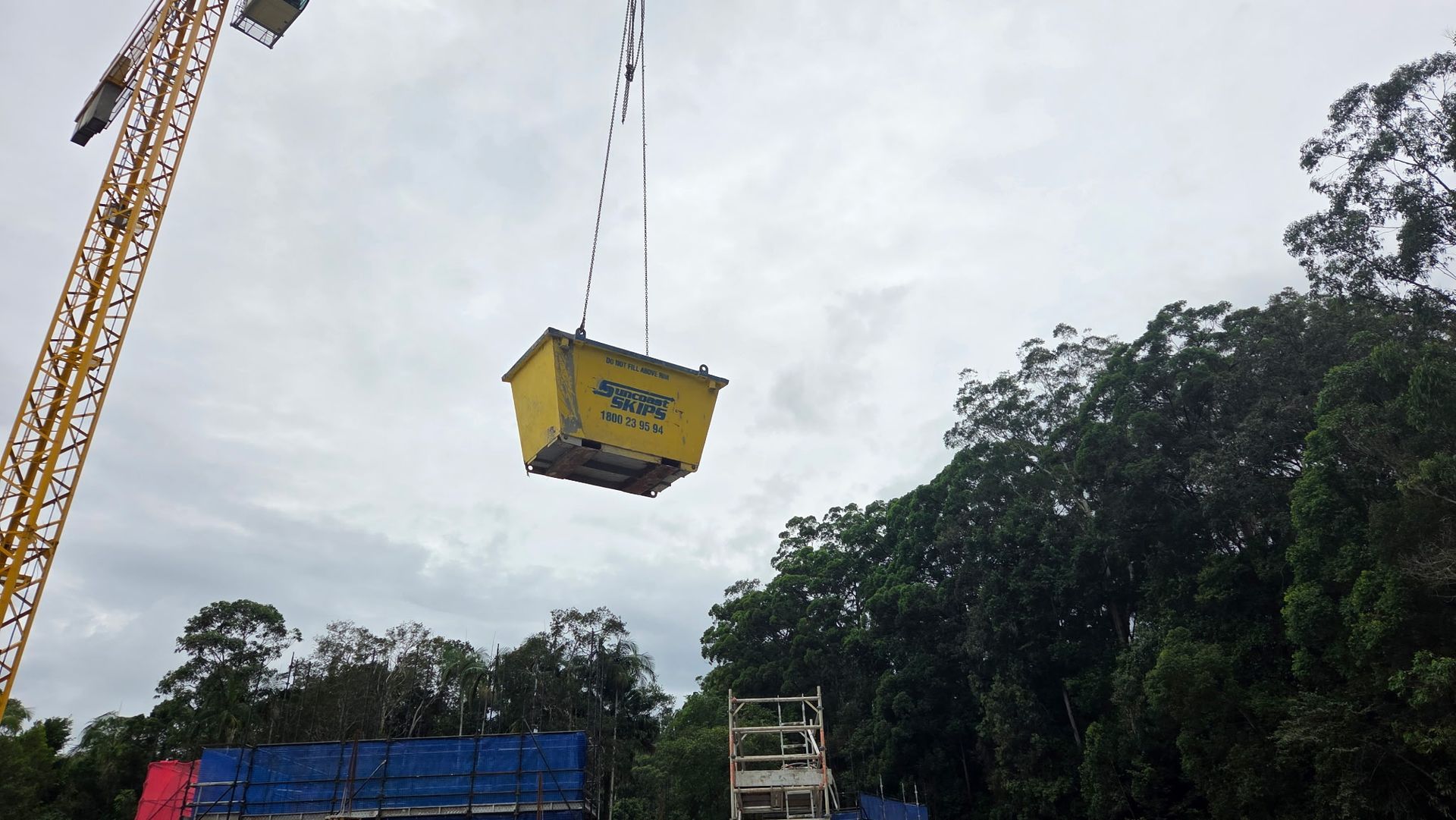 A yellow skip bin is being lifted in the air — Suncoast Skips in Coolum Beach, QLD