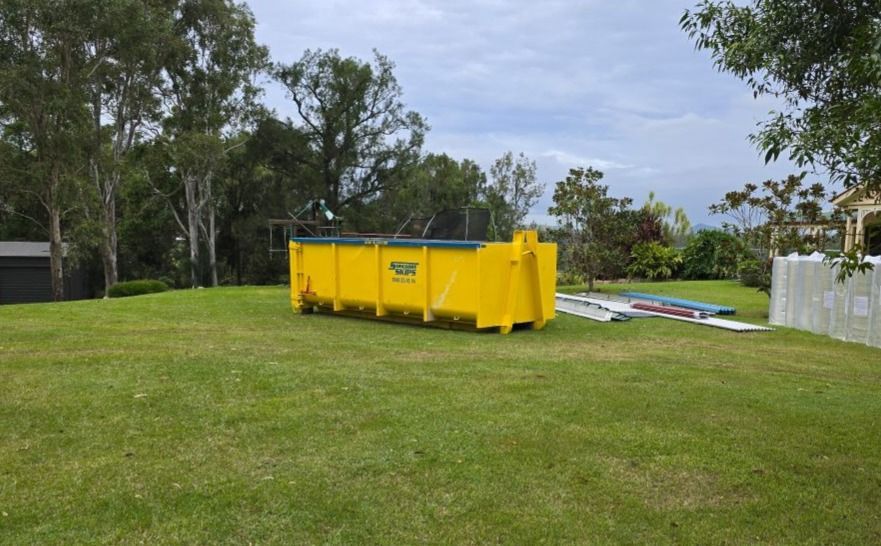 Large yellow hook bin sitting on the grass — Suncoast Skips in Coolum Beach, QLD