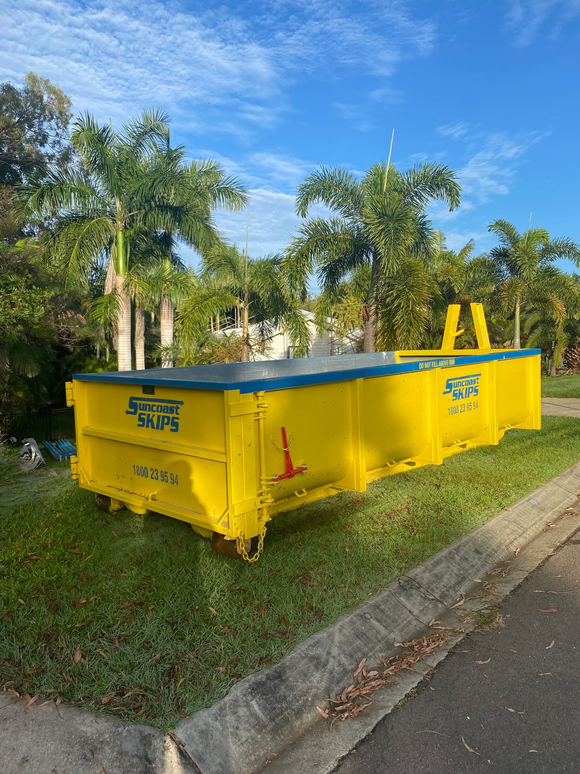 Yellow Skip bin on the grass next to palm trees — Suncoast Skips in Coolum Beach, QLD