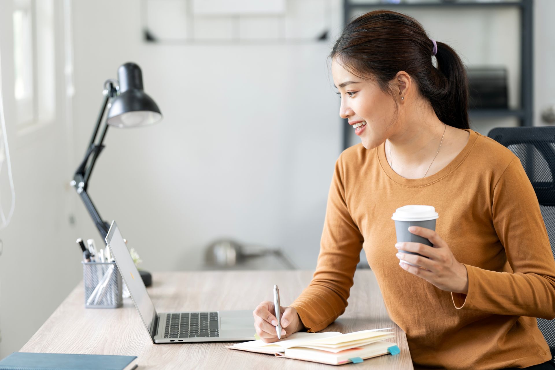 A woman is using a tablet computer in front of a computer screen.