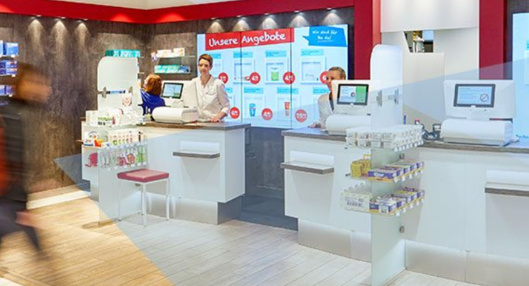 Ein verschwommenes Bild einer Apotheke mit Menschen, die an den Theken stehen.