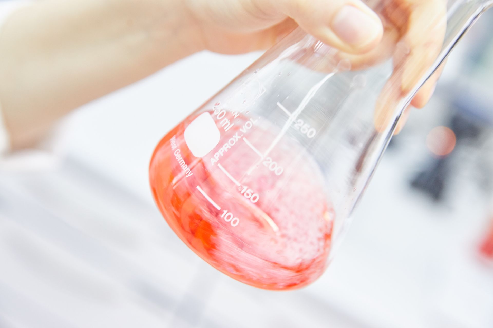 Eine Person hält einen Becher mit roter Flüssigkeit.