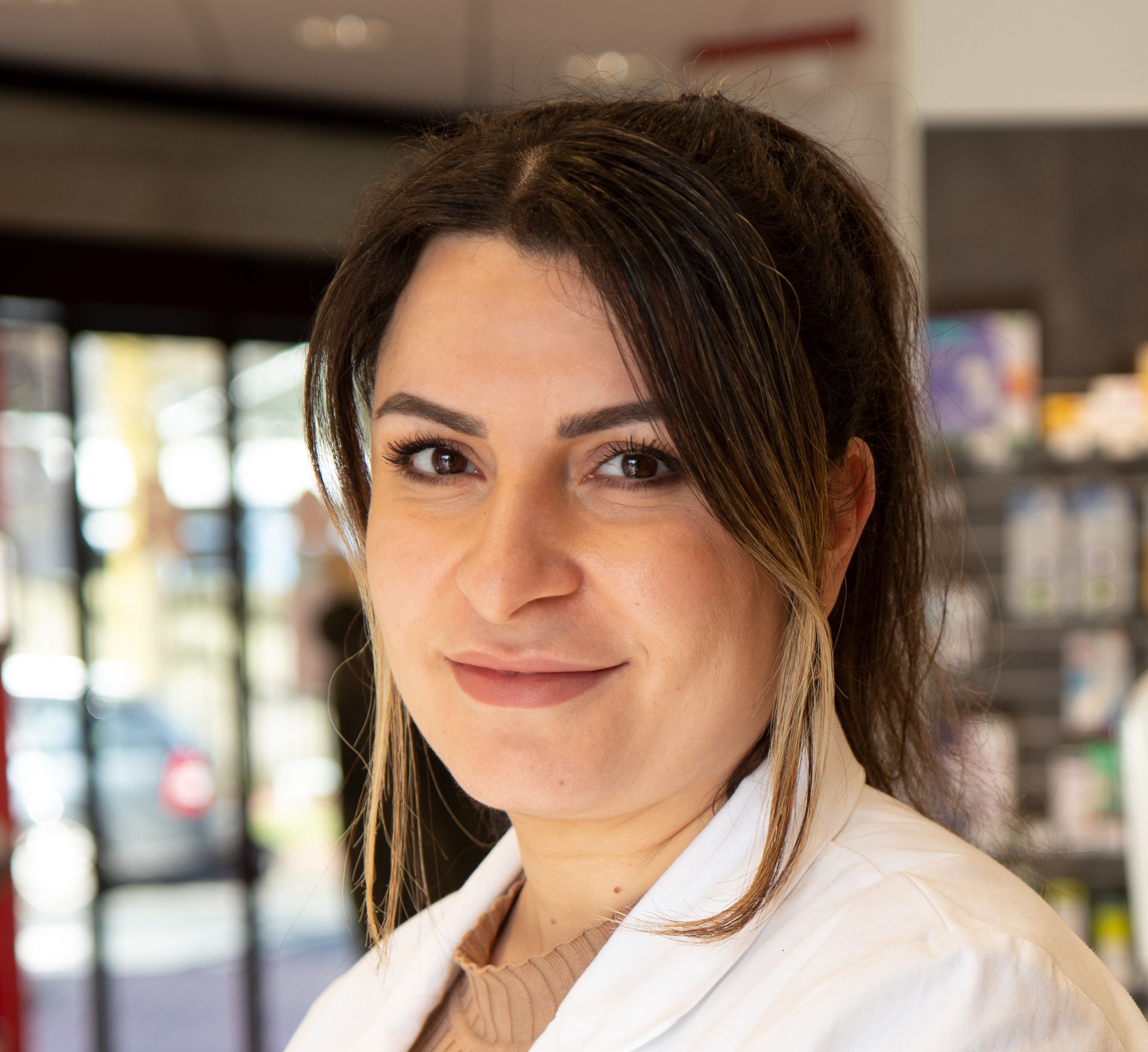 Eine Frau in einem weißen Laborkittel lächelt in die Kamera.