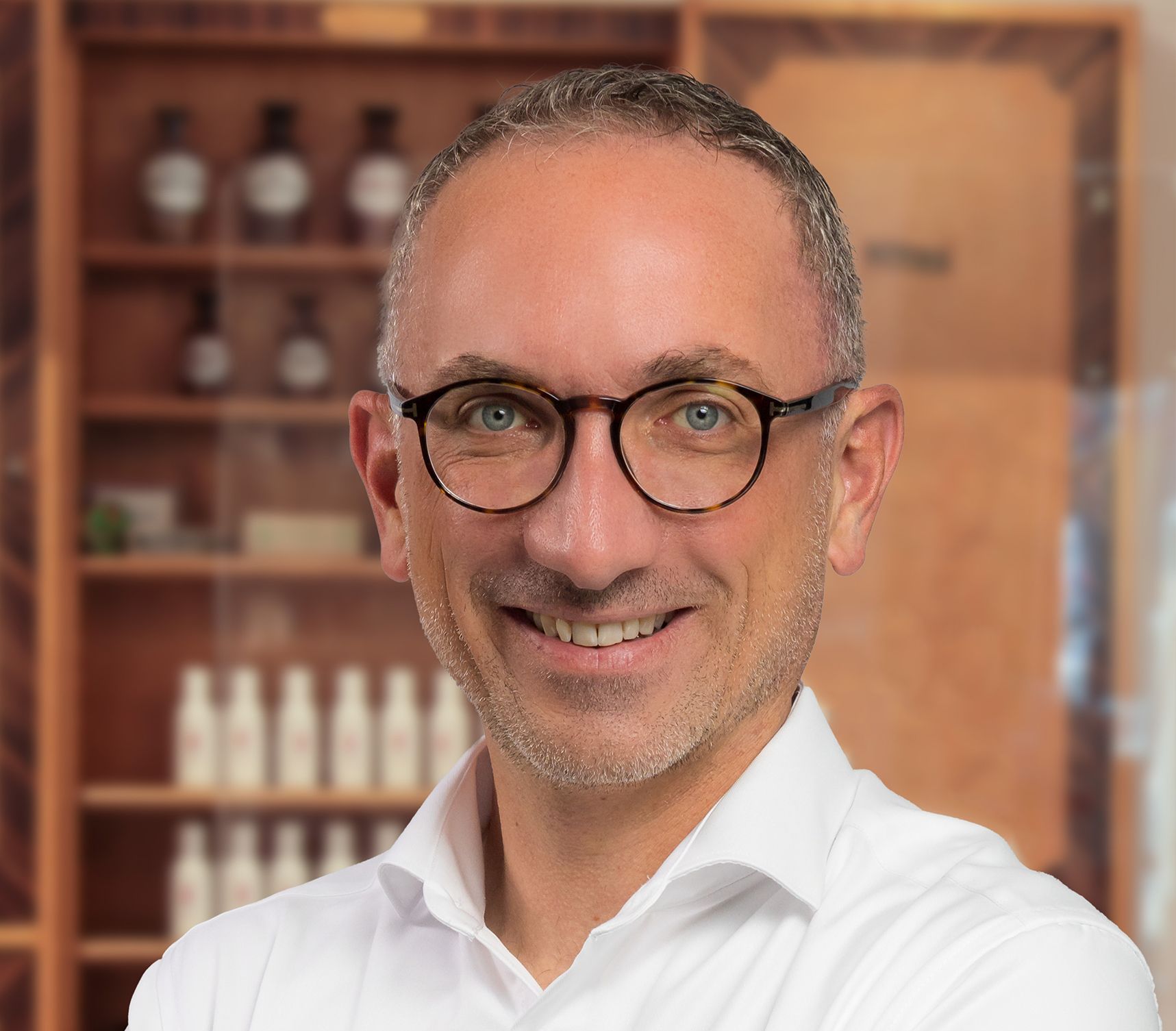 Ein Mann mit Brille und weißem Hemd lächelt in die Kamera