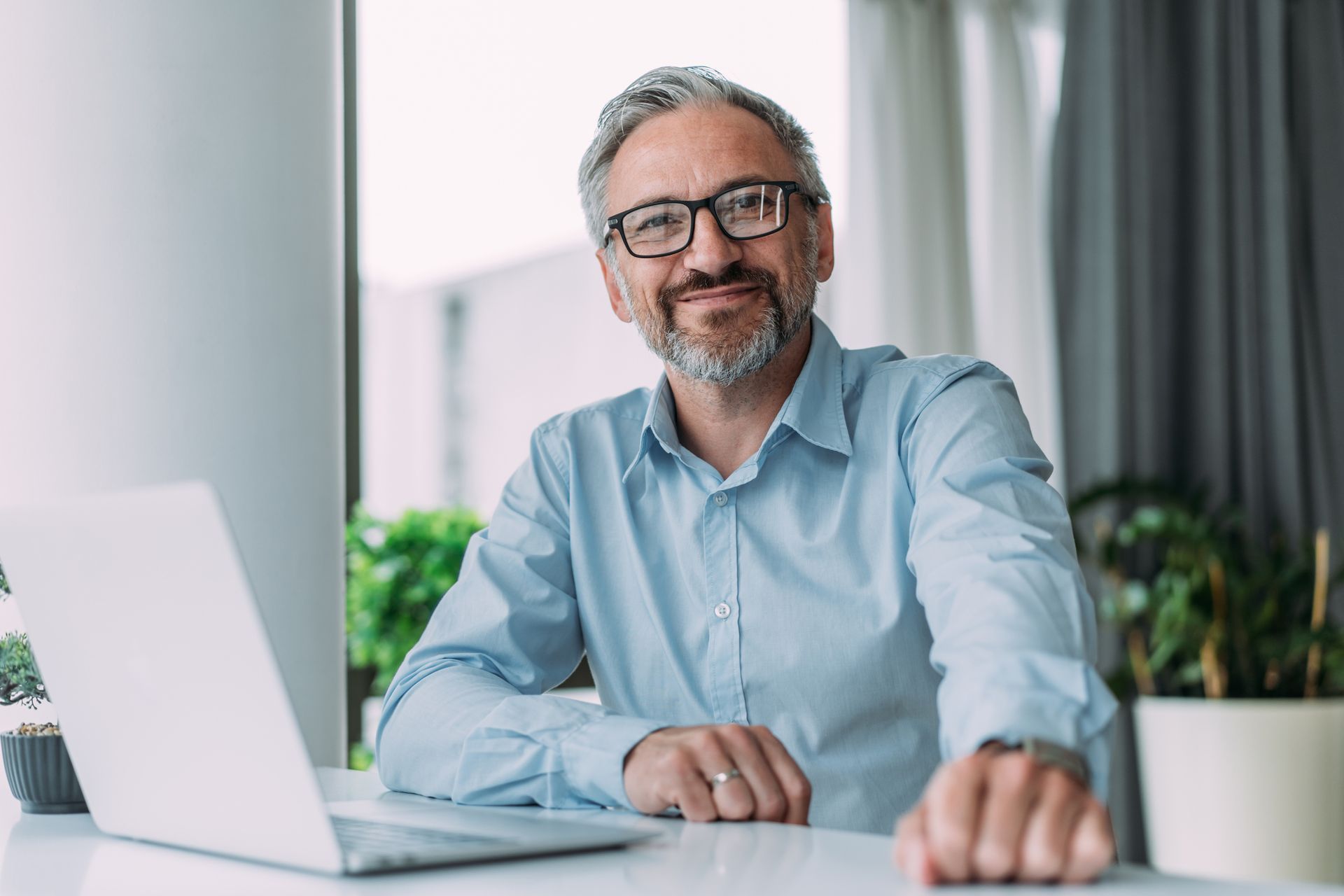 A man is sitting at a desk in front of a laptop computer.