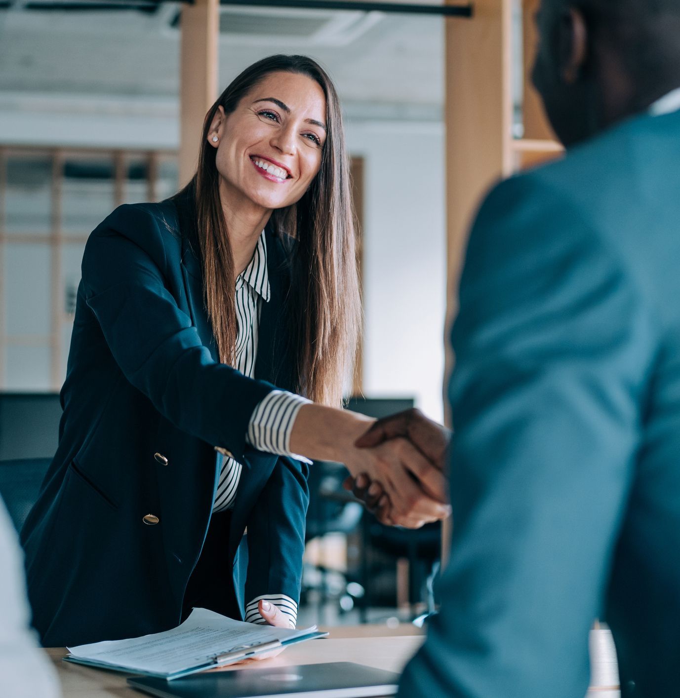 A woman is shaking hands with a man in an office.