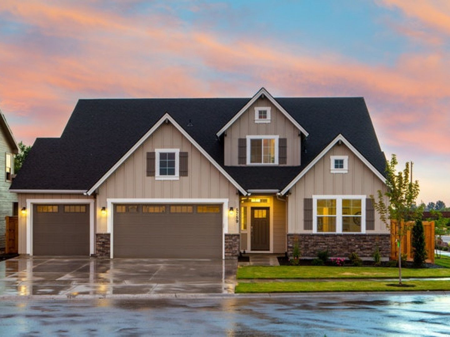 A large house with two garage doors and a driveway in front of it.