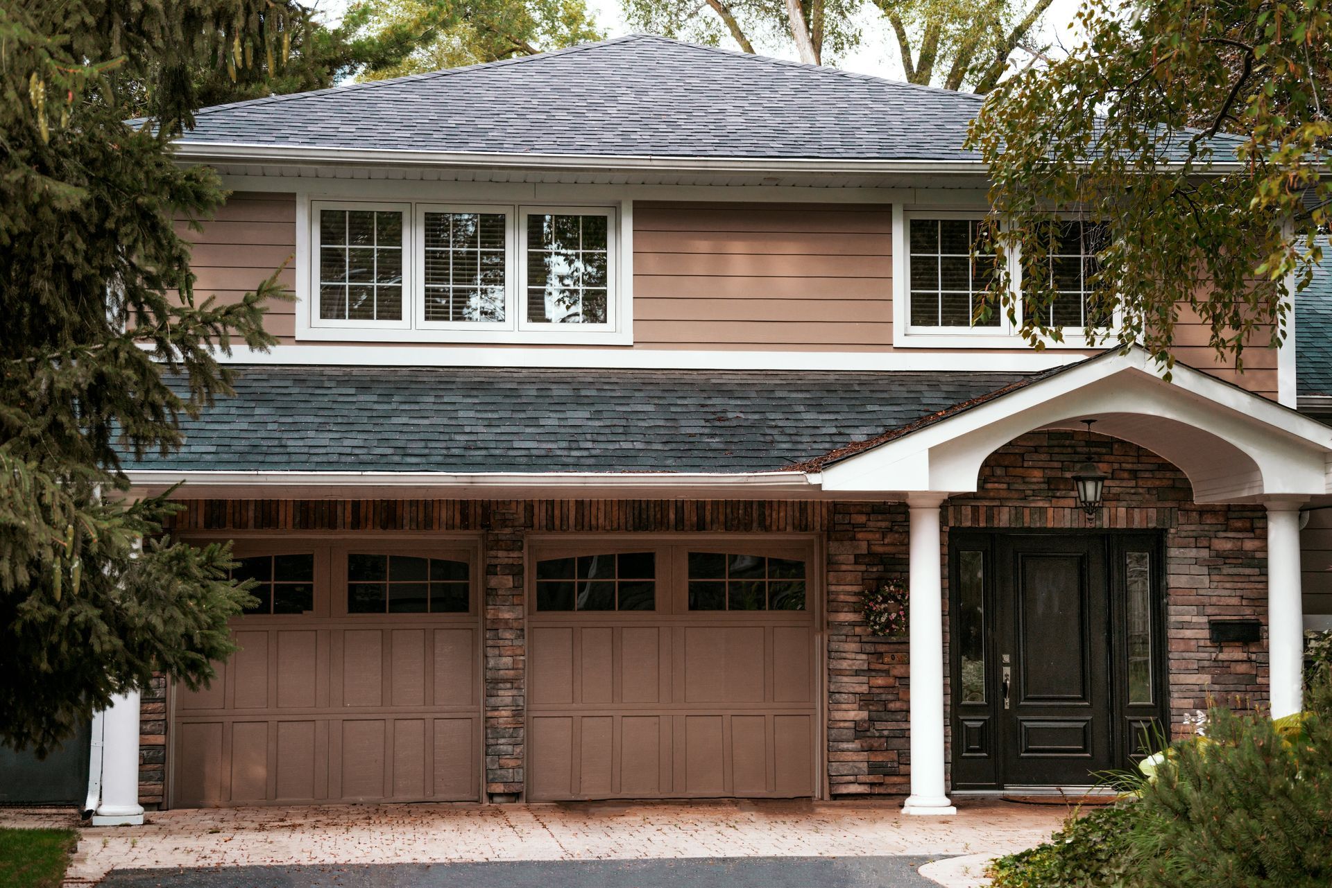 A large house with a blue roof and brown garage doors