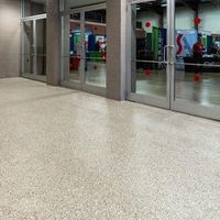A polished, light-colored speckled floor in front of glass doors opening into a conference hall.