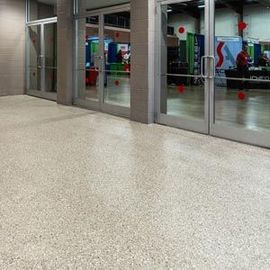 A polished, light-colored speckled floor in front of glass doors opening into a conference hall.