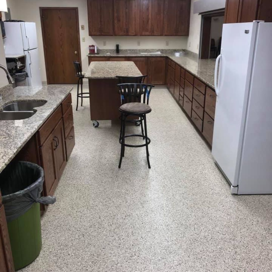 A kitchen featuring dark wood cabinets, granite countertops, a central island with stools, and a white refrigerator.