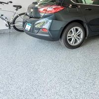A dark gray car parked in a garage with a light gray speckled epoxy floor and a bicycle leaning against the wall.
