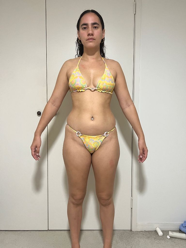 Woman in yellow bikini poses in front of a white door.