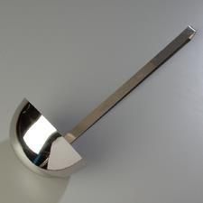 Cucharón de plata sobre una superficie gris, en ángulo, reflejando la luz.