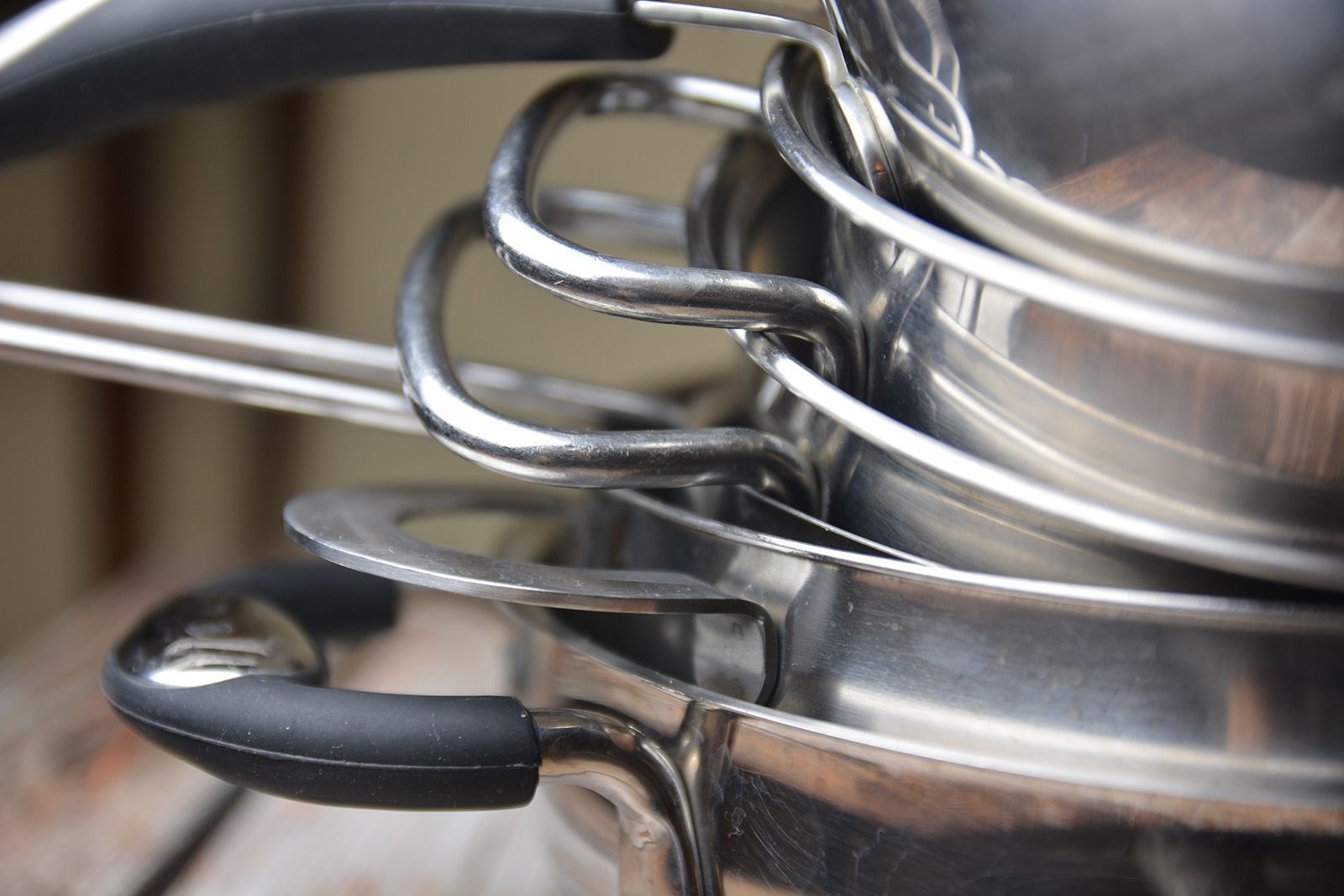 Pila de ollas de acero inoxidable con asas metálicas curvadas.