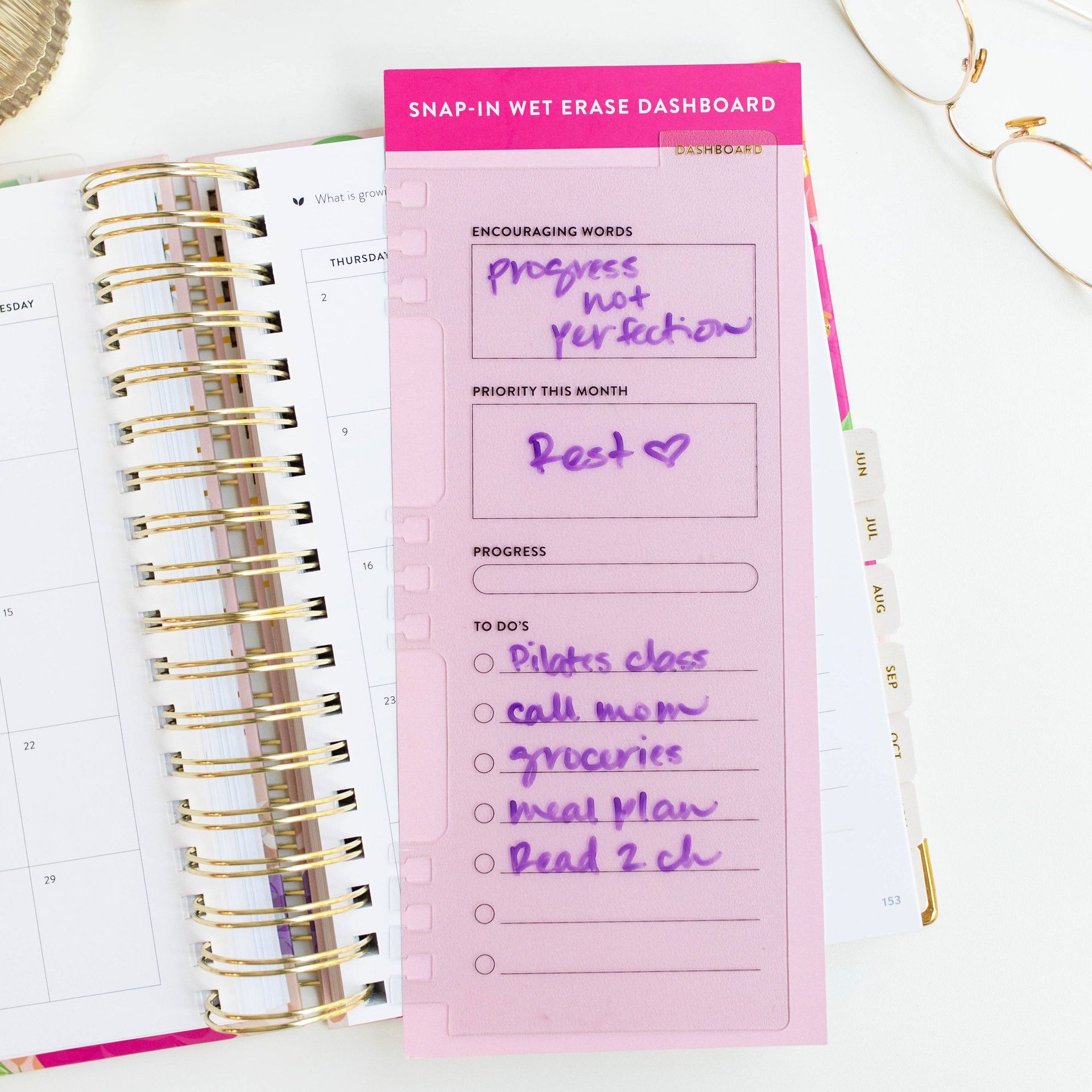 A notebook with a pink dashboard that says progress not perfection