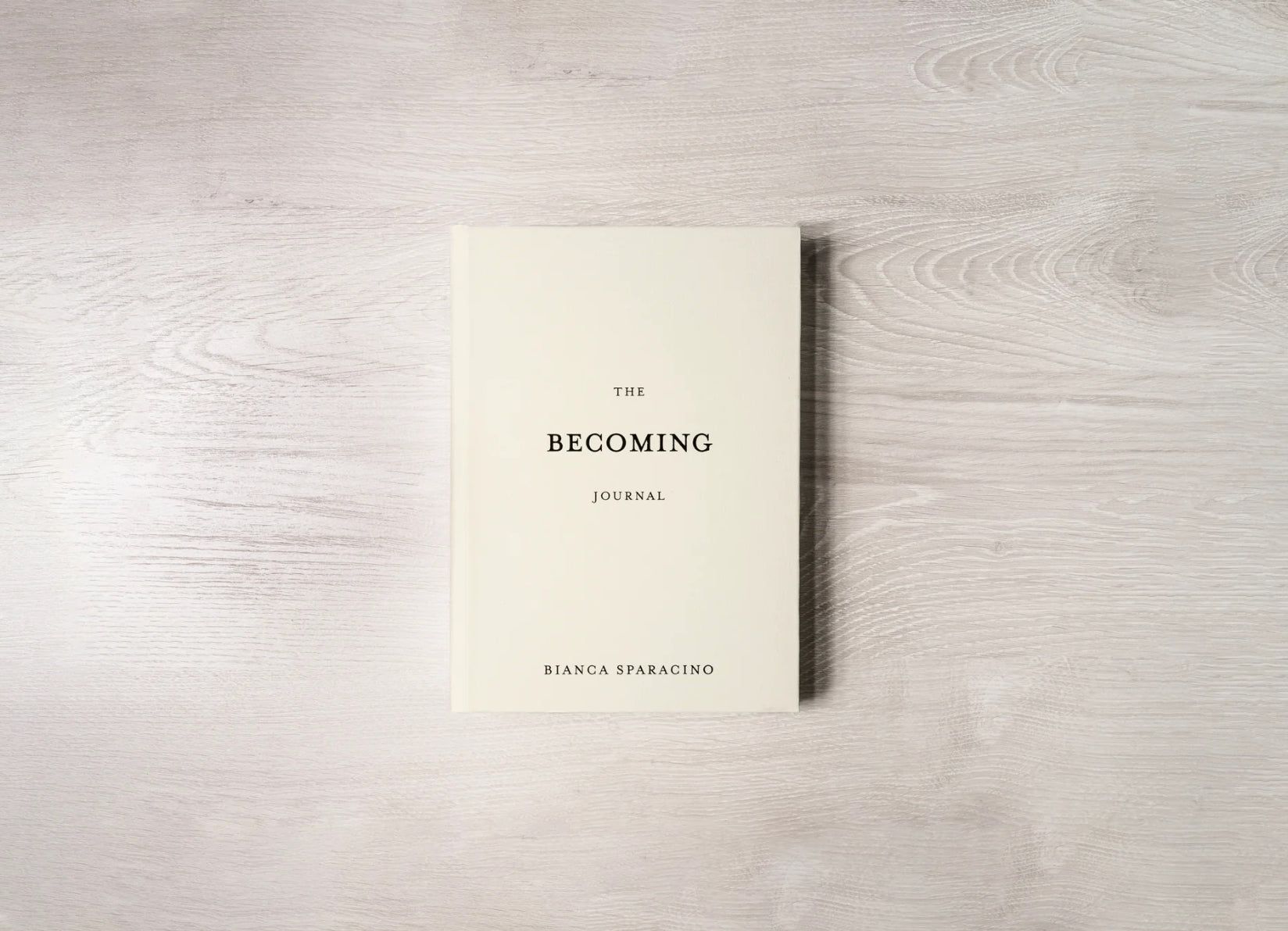 A white book is sitting on a wooden table.